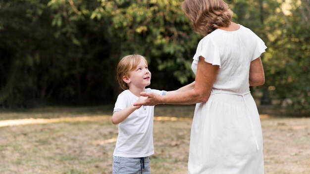 ミディアムショットのおばあちゃんと手をつないでいる子供