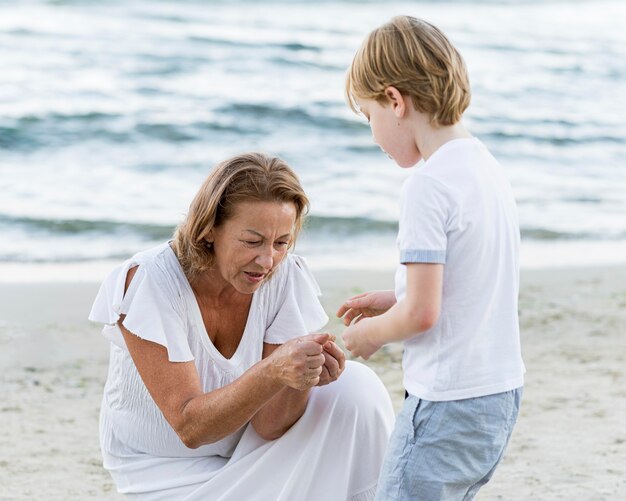 Бабушка и ребенок среднего размера на берегу моря
