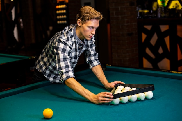 Medium shot guy arranging balls with triangle 