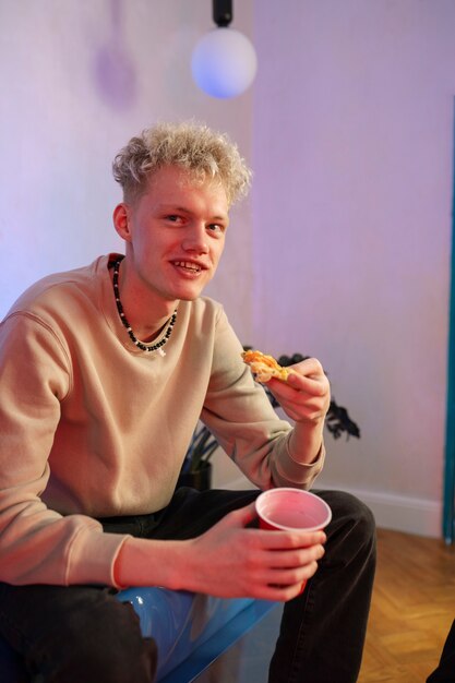 Free photo medium shot guy holding pizza slice