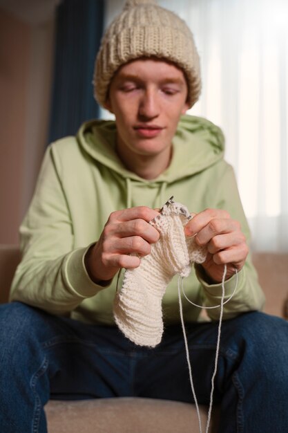 medium shot guy knitting with white yarn