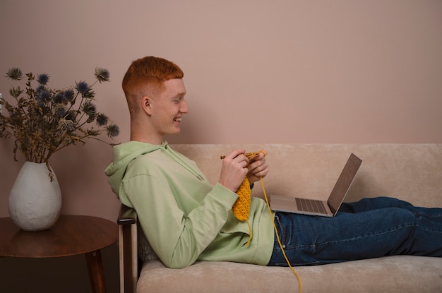 Medium shot guy knitting with yellow yarn