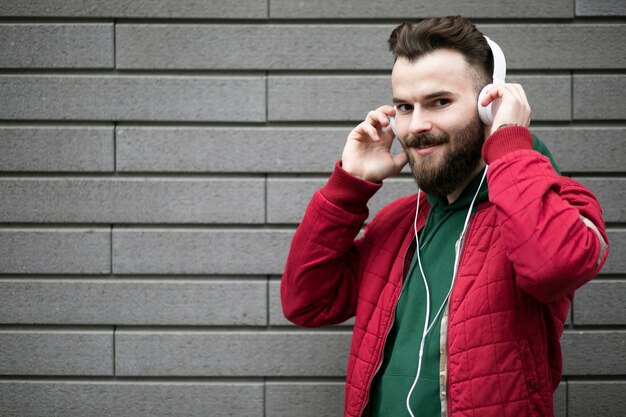 Medium shot guy with headphones near brick wall