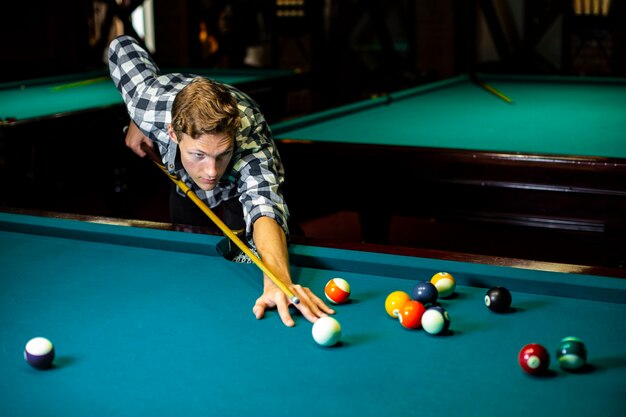 Medium shot guy with pool cue and billiard table 