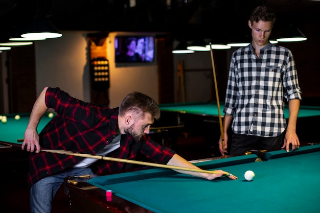 Medium shot guys playing billiard together