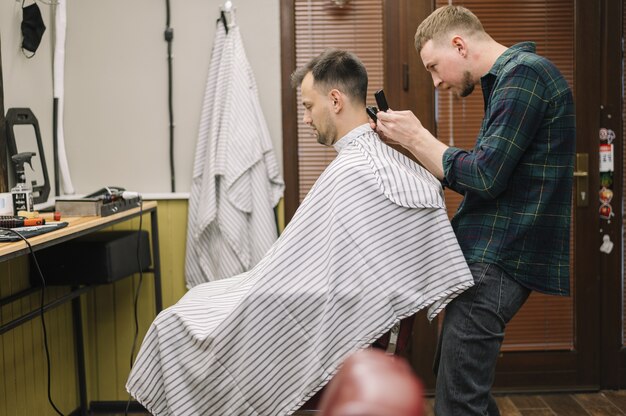 Free photo medium shot of hairstilyst giving a haircut