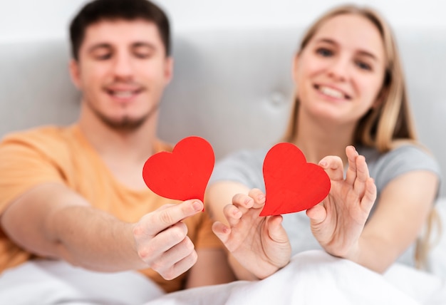 Medium shot happy blurred couple holding heart shaped paper