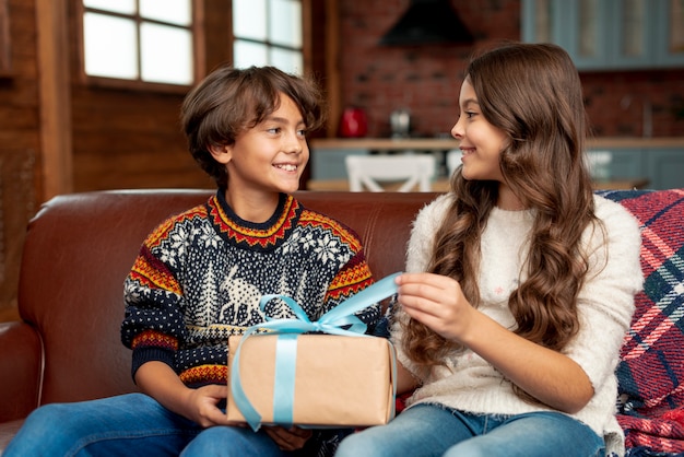 Средний снимок счастливых детей с подарком