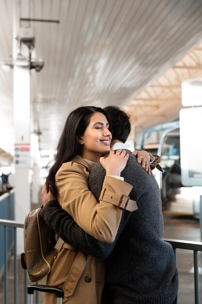 Foto gratuita coppie felici del colpo medio che si abbracciano all'aeroporto