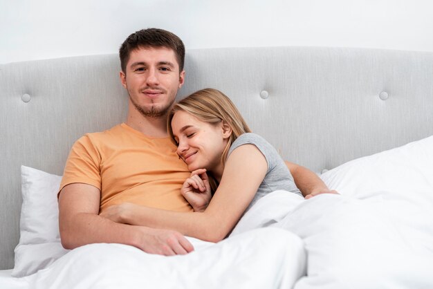 Средний снимок счастливая пара лежит в постели
