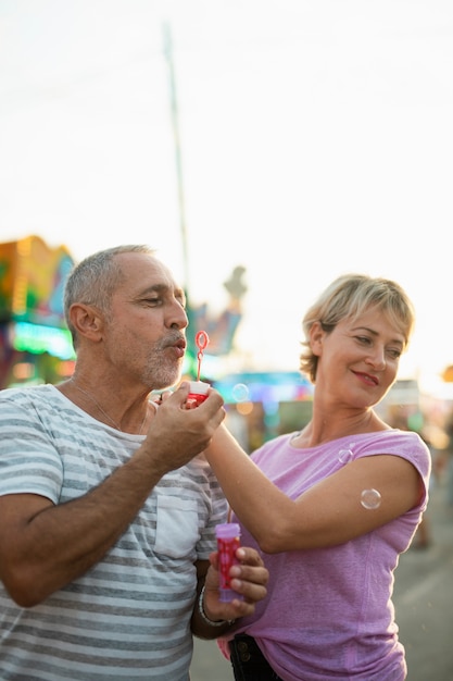 Free photo medium shot happy couple making soap bubbles