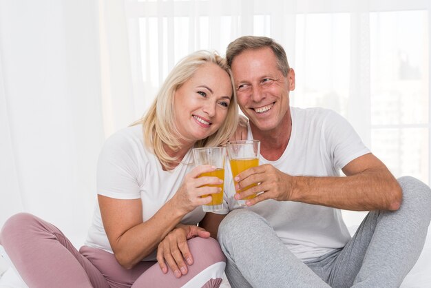 Medium shot happy couple making a toast with juice