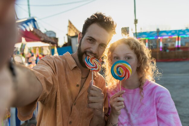 Medium shot happy couple with lollipops taking a selfie