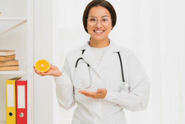 Medium shot happy doctor holding up an orange