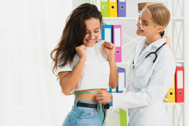 Medium shot happy doctor measuring girl