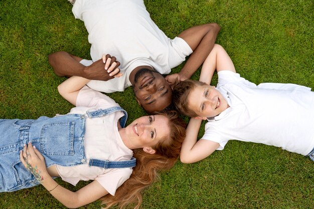 Medium shot happy family laying on grass