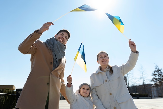 Счастливая семья среднего размера с украинскими флагами