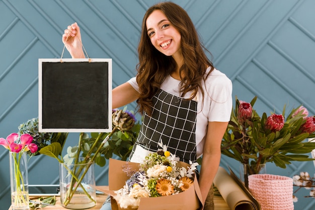 Free photo medium shot happy florist holding a black board