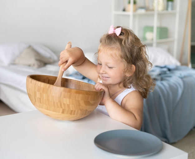 Foto gratuita ragazza felice del colpo medio che mangia alla tavola