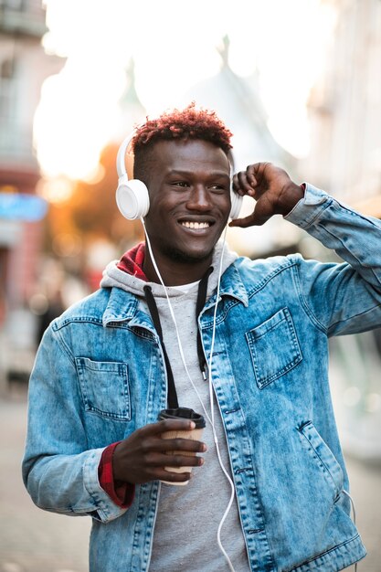 Medium shot happy guy with headphones and coffee cup