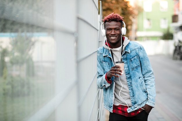 Medium shot happy guy with headphones and coffee cup