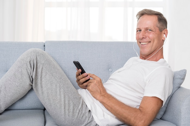 Free photo medium shot happy man with headphones on the couch