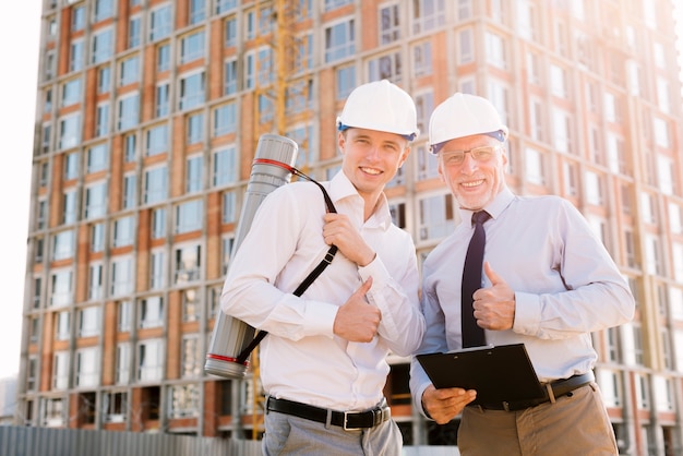 Medium shot happy men with helmets looking at camera