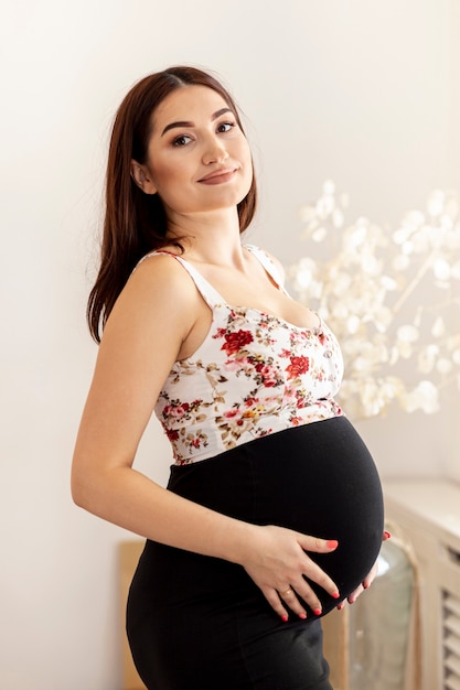 Medium shot happy pregnant woman posing indoors