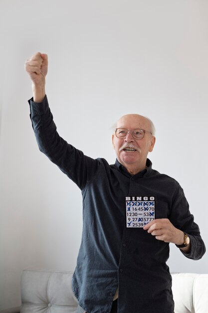 Medium shot happy senior man playing bingo