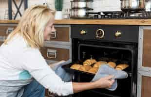 Free photo medium shot happy woman baking croissants