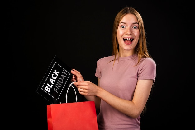 Medium shot of a happy woman holding a black friday card