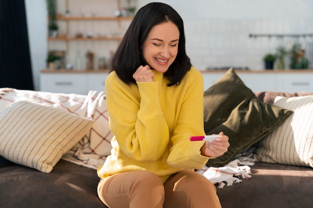 Medium shot happy woman holding pregnancy test