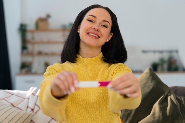 Free photo medium shot happy woman holding pregnancy test