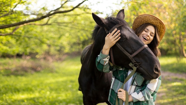 ミディアムショットの幸せな女性と馬