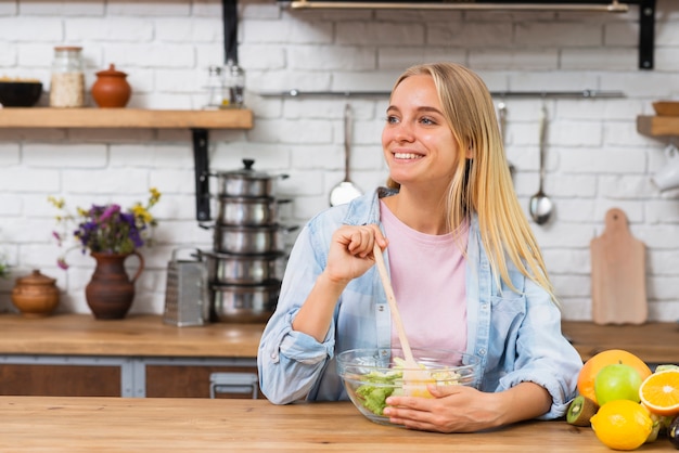 Medium shot happy woman making a salad