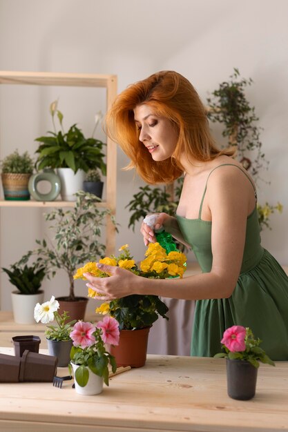 Средний снимок счастливая женщина поливает цветок