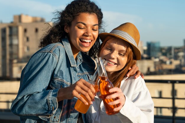 Medium shot happy women clinking bottles