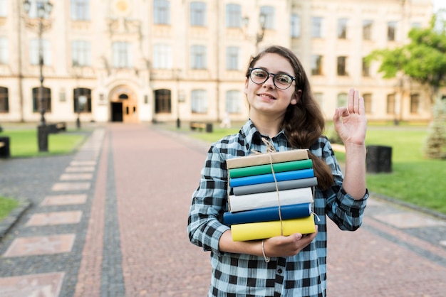 Medium shot of highschool girl holding books in hands