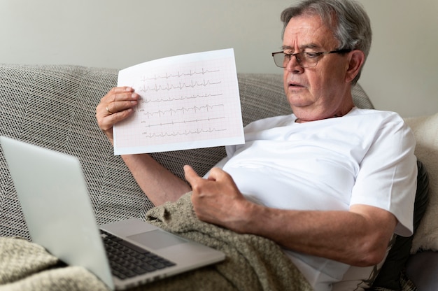 Medium shot ill man on couch with laptop