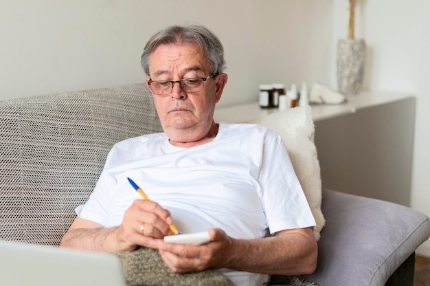 Medium shot ill man on couch with notebook