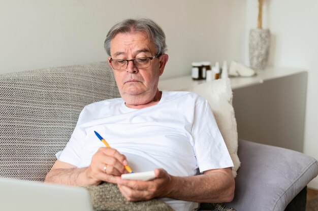 Medium shot ill man on couch with notebook