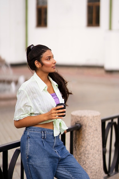 Индийская женщина среднего роста держит чашку кофе