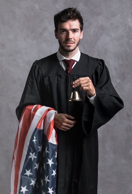 Medium shot judge in robe with flag and bell