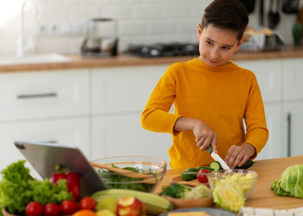 Foto gratuita ragazzo di tiro medio che cucina in cucina