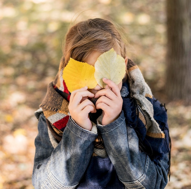 葉で顔を覆うミディアムショットの子供