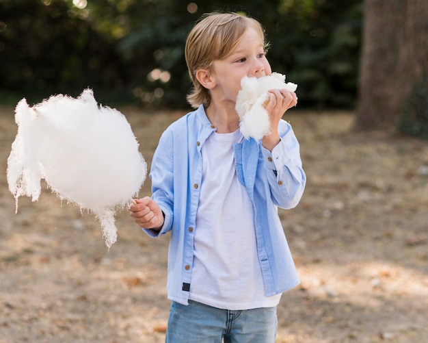 Free photo medium shot kid eating cotton candy