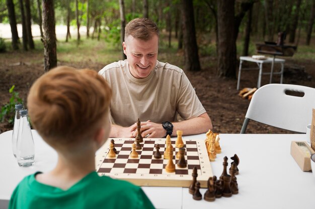 Medium shot kid and father playing chess