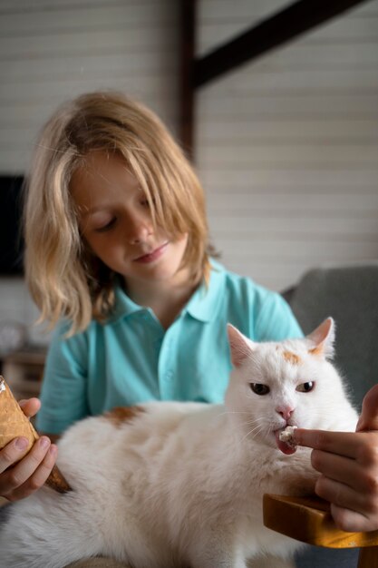 ミディアムショットの子供が猫に餌をやる