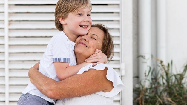 Medium shot kid and grandma hugging