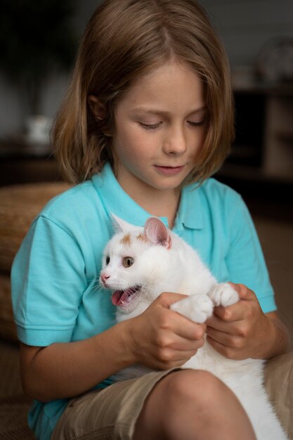 愛らしい猫を抱いたミディアムショットの子供